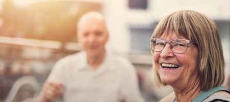 elderly woman smiling at café blurred man in background