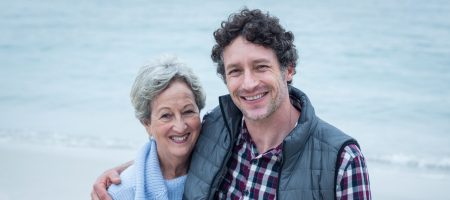 Happy mid adult man with elderly mother at sea shore