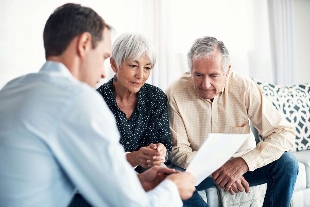 elderly couple and man holding paper sitting down