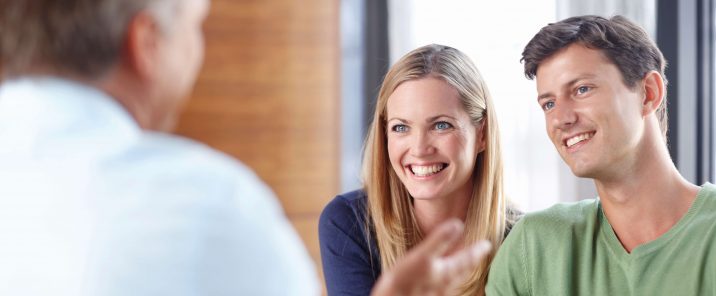 smiling man and woman talking to over the shoulder man