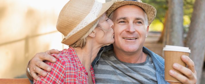 woman kissing man on cheek man holding hot drink cup