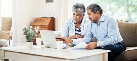 man and woman on sofa pointing at laptop