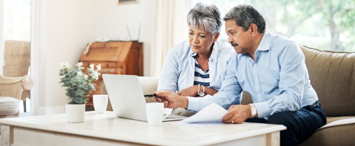 man and woman on sofa pointing at laptop