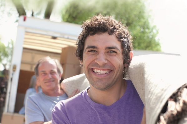 close up two men carrying rolled up carpet