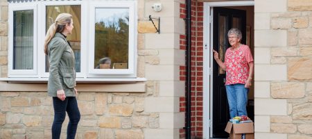 woman leaving other woman package at front door