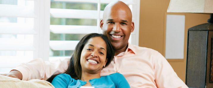 man and woman smiling sitting on sofa