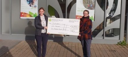 Two women holding mansfield cheque for schools out