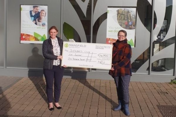 Two women holding mansfield cheque for schools out