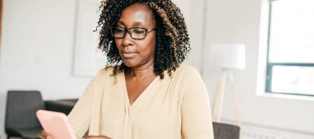 Woman looking at pink phone at desk