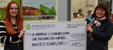 Two women holding mansfield bs cheque st andrews primary school