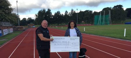 Dog man woman holding cheque on running track