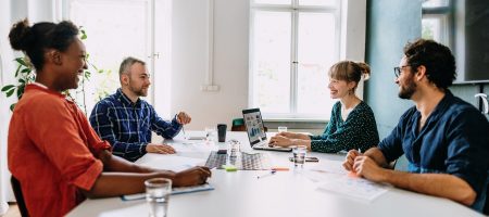 Four people in office talking at table