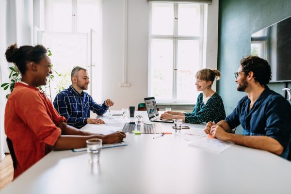 Four people in office talking at table