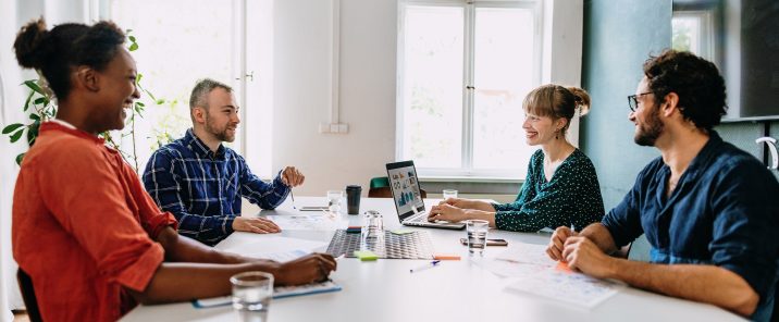 Four people in office talking at table