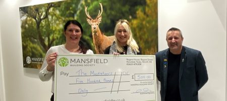 Man and two women holding mansfield bs cheque in front of deer image