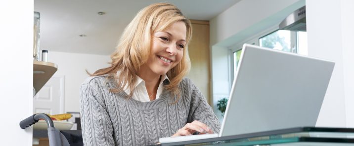 A disabled woman In her wheelchair using a laptop at home